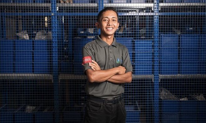 Corporate portrait of a warehouse worker in front of blue storage racks